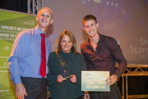 Linda Holmes wins award with Andrew Bowden our Chief Executive and Ash Dykes at our Colleague Conference 2016 at Venue Cymru