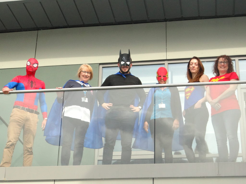 Our coworkers stand on the balcony and wearing various superhero costumes